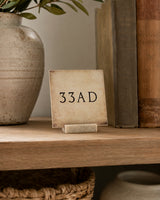 33AD 4x4 Christian Shelf Sitter in a natural wood stand on a rustic shelf beside a neutral vase and vintage books.