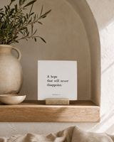 A Hope That Will Never Disappoint 4x4 Christian shelf sitter with natural wood base, styled in a arched alcove shelf scene.