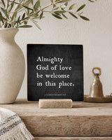 Almighty God of Love 4x4 Christian Shelf Sitter on a rustic console with olive branches, a neutral vase, and a brass bell.