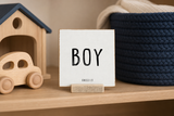 “Boy,” a 4 x 4-inch shelf sitter in the black text on white finish, styled on a toy car shelf.