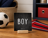 “Boy” 4 x 4-inch shelf sitter in the white text on black distressed finish, displayed on a sports bedroom desk.