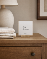 Drop the Stone 4x4 Christian shelf sitter with natural wood base, styled in a guest room dresser scene.