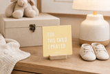 “For This Child I Prayed” 4 x 4-inch shelf sitter in the black lettering on yellow finish, displayed in a new baby gift basket.
