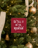 Red 4x4 Go Tell It on the Mountain ornament with metal wire hanger on a Fraser fir with ivory velvet ribbon and warm lights.