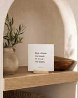 God Offends Our Minds to Reveal Our Hearts 4x4 Christian shelf sitter with natural wood base, styled in a arched alcove shelf scene.