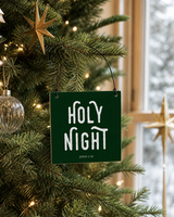 Dark Green 4x4 Holy Night ornament with metal wire hanger on an elegant fir near a winter window with brass stars and soft lights.