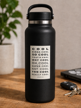 Black water bottle with text label on a wooden surface