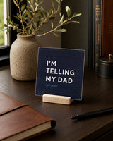 I'm Telling My Dad 4x4 Christian Shelf Sitter on a dark desk with an olive branch vase, leather notebook, and pen.