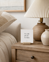 I've Still Got Joy in Chaos 4x4 Christian shelf sitter with natural wood base, styled in a coastal bedside table scene.