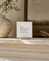 In the Kingdom of God Your Opinion Does Not Count 4x4 Christian shelf sitter with natural wood base, styled in a limestone living room mantel scene.