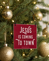 Red 4x4 Jesus Is Coming to Town ornament with metal wire hanger on a noble fir with champagne glass ornaments and warm pinpoint lights.