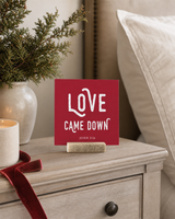 Red 4x4 Love Came Down Christmas Shelf Sitter in a christmas guest room with its rustic wood slot stand.