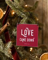 Red 4x4 Love Came Down ornament with metal wire hanger on a farmhouse tree with dried orange, cinnamon velvet ribbon, and warm lights.