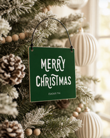 Dark Green 4x4 Merry ornament with metal wire hanger on a flocked tree with wooden bead garland and cream ornaments.