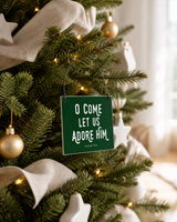 Dark Green 4x4 O Come Let Us Adore Him ornament with metal wire hanger on a neutral tree with white ceramic stars and linen ribbon.