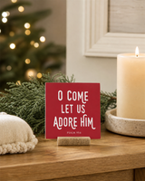 Red 4x4 O Come Let Us Adore Him Christmas Shelf Sitter in a advent prayer corner with its rustic wood slot stand.