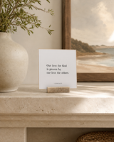 Our Love for God Is Proven by Our Love for Others 4x4 Christian shelf sitter with natural wood base, styled in a limestone living room mantel scene.