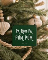 Dark Green 4x4 Pa-Rum-Pa-Pum-Pum ornament with metal wire hanger on a modern farmhouse tree with pale wood ornaments and woven garland.