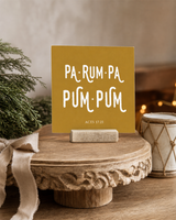 Gold 4x4 Pa-Rum-Pa-Pum-Pum Christmas Shelf Sitter in a formal living room pedestal with its rustic wood slot stand.