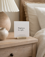 Singleness Is a Gift 4x4 Christian shelf sitter with natural wood base, styled in a coastal bedside table scene.