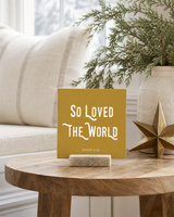 Gold 4x4 So Loved the World Christmas Shelf Sitter in a window seat side table with its rustic wood slot stand.
