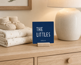 Close-up of “The Littles,” a 4 x 4-inch shelf sitter in the white lettering on blue finish on a nursery dresser.