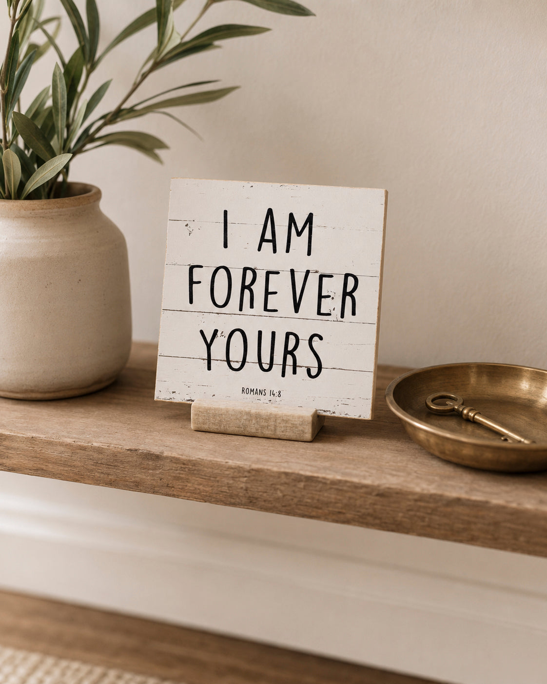 I Am Forever Yours 4x4 Christian Shelf Sitter on a narrow wood console with potted olive branches, a brass tray, and a key.